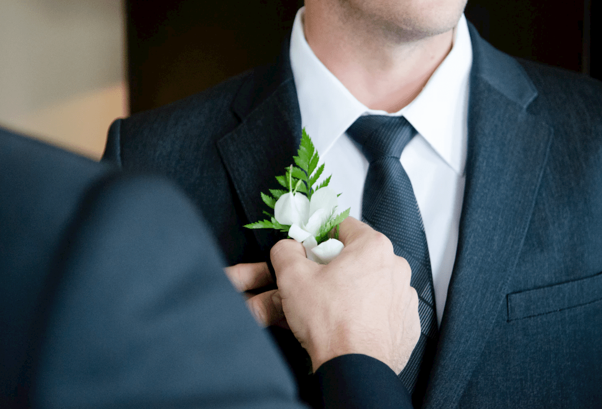 Best man pinning a flower to the groom before the wedding
