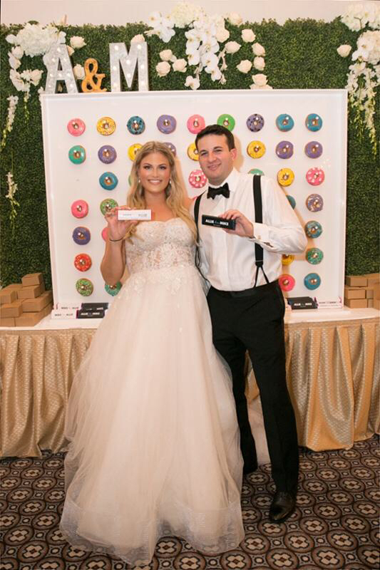 Alexandra & Mike in front of their donut wall