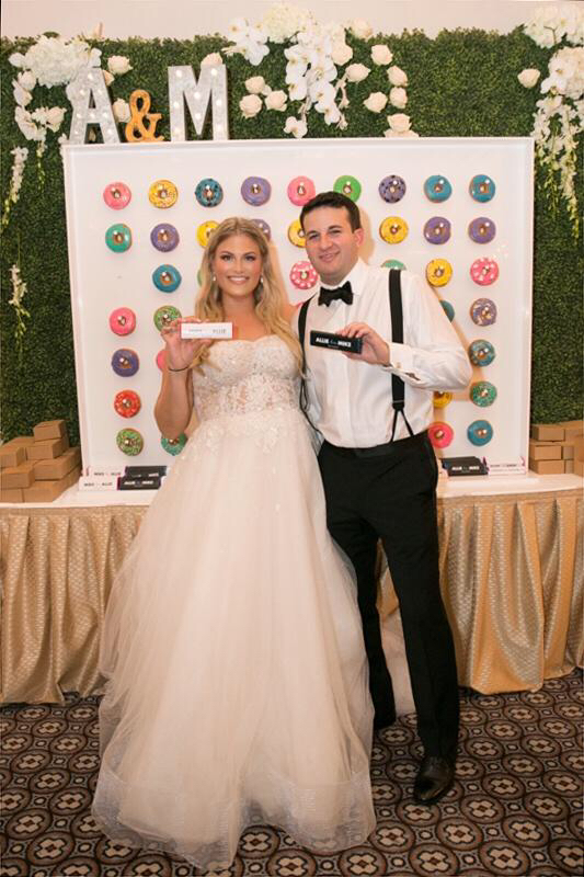 Alexandra & Mike in front of their donut wall
